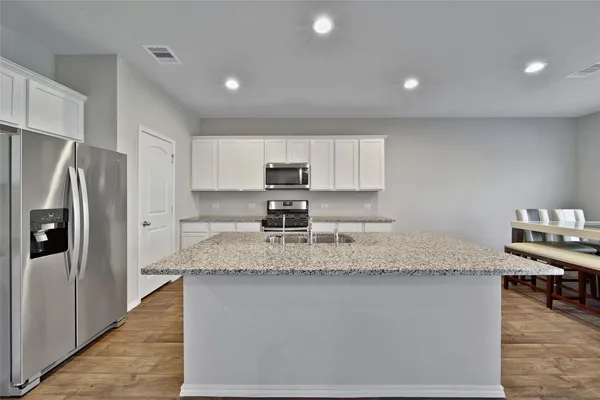 a kitchen with stainless steel appliances granite countertop a sink refrigerator and cabinets