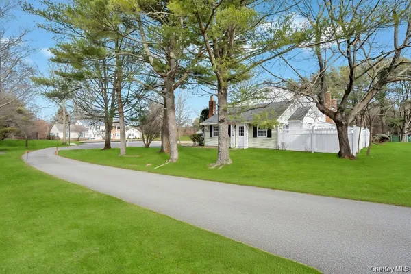 a view of house with a big yard and large trees