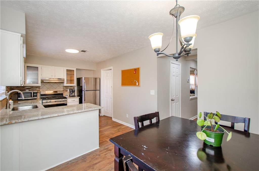 1066 Wedgewood Lane Tucker, GA 30084 - Photo 13 of 23 a kitchen with stainless steel appliances granite countertop a sink dishwasher a stove a refrigerator a dining table and chairs with wooden floor