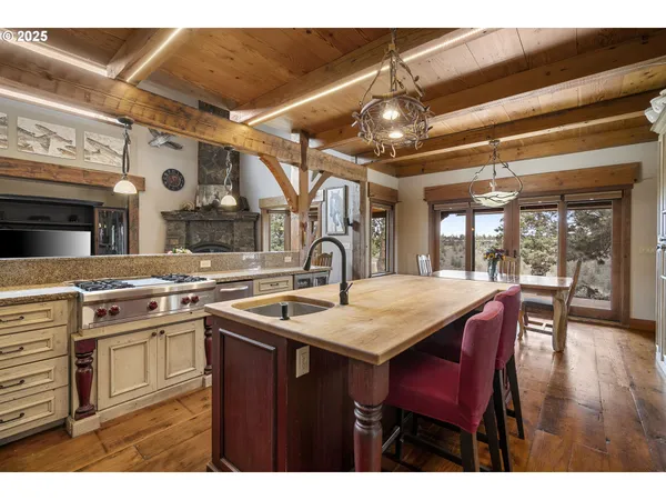 a kitchen with stainless steel appliances granite countertop a stove a refrigerator a dining table and chairs with wooden floor