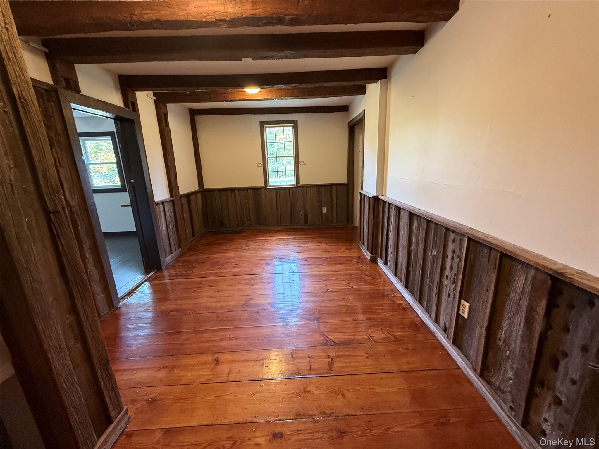 241 White Bridge Road Middletown, NY 10940 - Photo 10 of 29 Empty room featuring a wainscoted wall, wood-type flooring, wood walls, and beamed ceiling