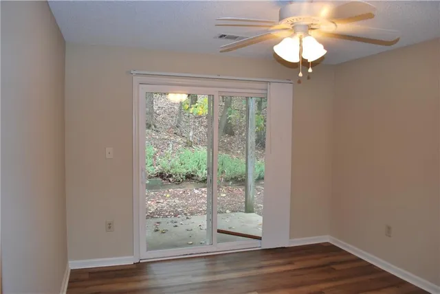 a view of a livingroom with wooden floor a ceiling fan and a window