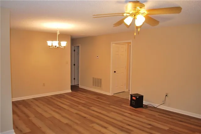 an empty room with wooden floor and fan