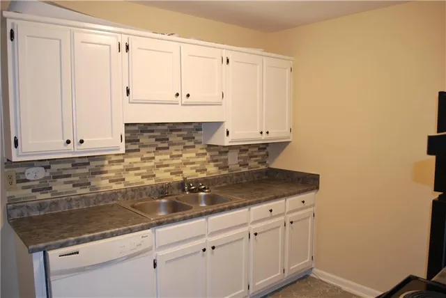 a kitchen with granite countertop white cabinets and a sink