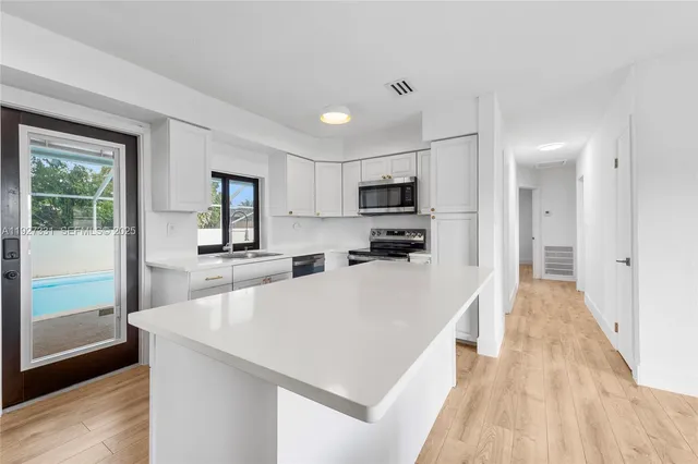 a large white kitchen with wooden floor and a sink