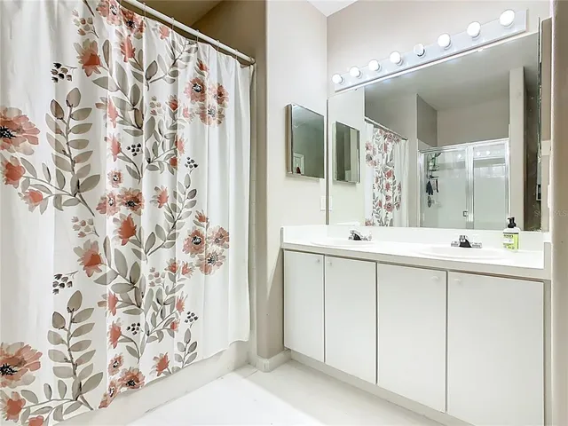 a bathroom with a double vanity sink a mirror a shower and a bathtub