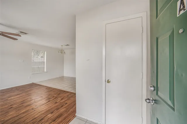 a view of empty room with wooden floor and fan