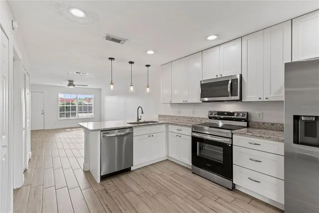 a kitchen with stainless steel appliances granite countertop a stove top oven a sink dishwasher and a refrigerator