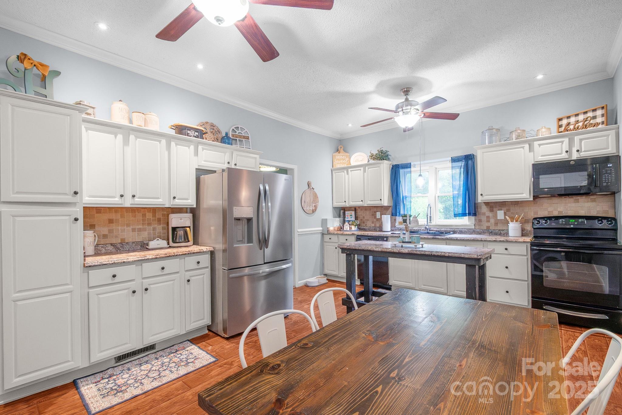 2578 Laboratory Road Lincolnton, NC 28092 - Photo 13 of 34 a kitchen with stainless steel appliances kitchen island granite countertop a refrigerator a stove a sink dishwasher and white cabinets with wooden floor