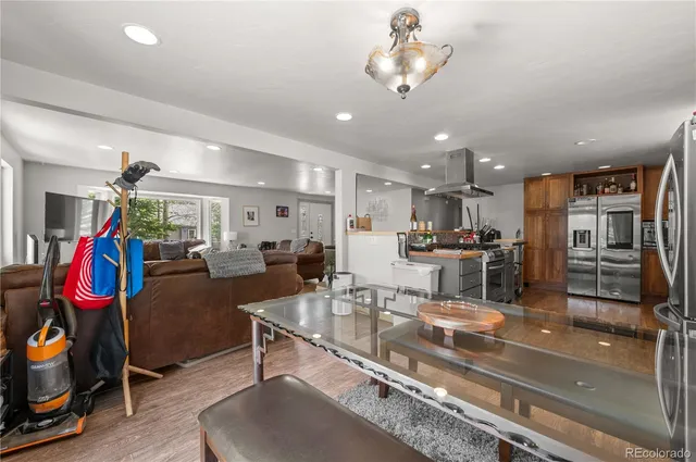 a large kitchen with stainless steel appliances kitchen island granite countertop a large stove a sink dishwasher and white cabinets with wooden floor