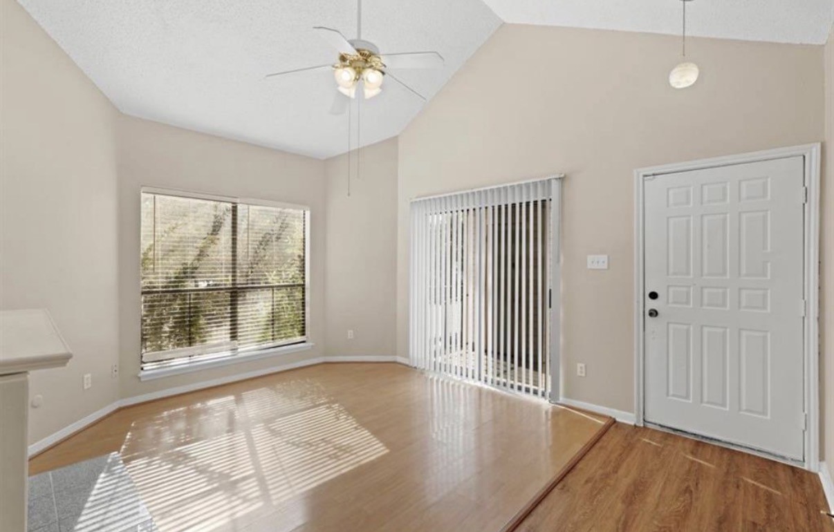 an empty room with wooden floor and windows