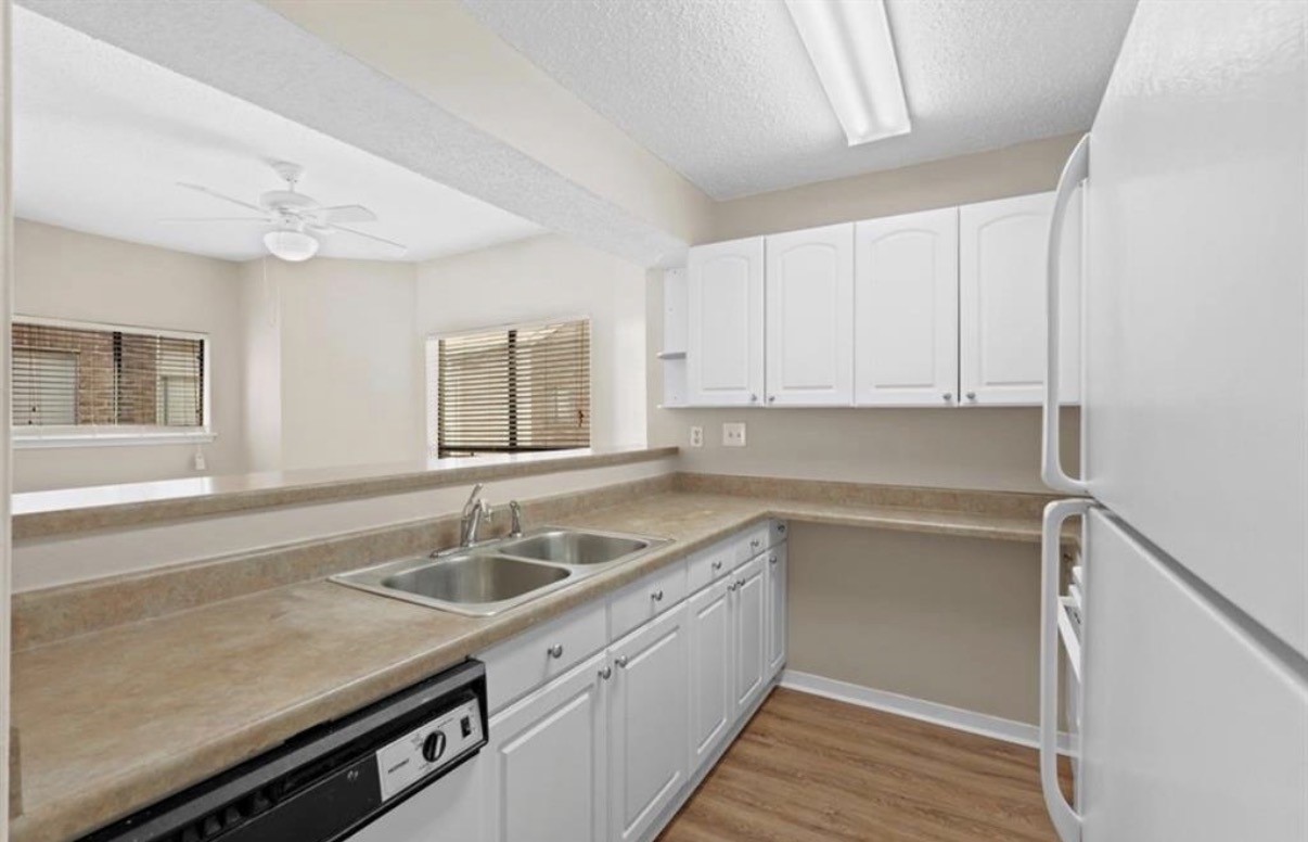 10164 Oakberry Street Houston, TX 77042 - Photo 4 of 8 a kitchen with a sink dishwasher a stove and white cabinets with wooden floor
