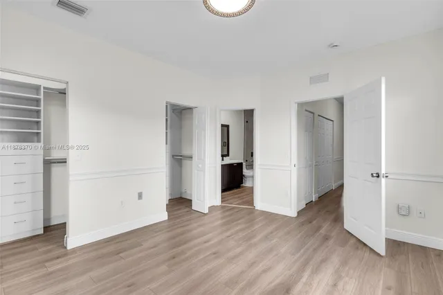 an empty room with wooden floor & cabinet and a window