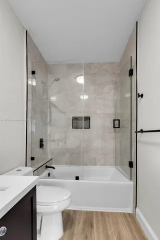 a bathroom with a bathtub shower sink mirror and toilet