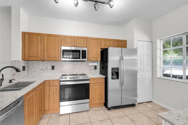 a kitchen with stainless steel appliances granite countertop a refrigerator sink and microwave
