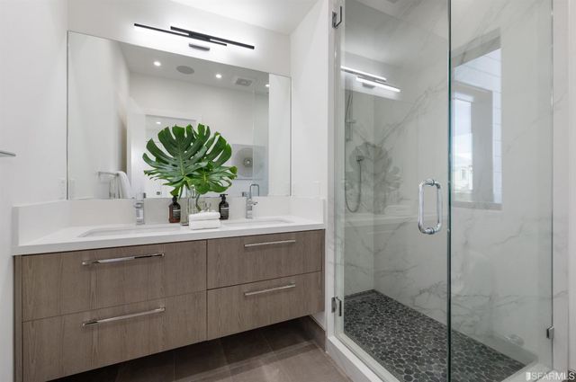 a bathroom with a granite countertop sink a mirror and a shower