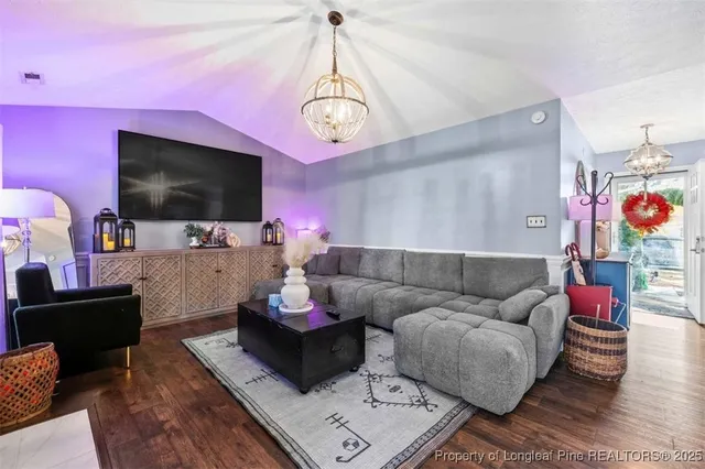 a view of a dining room and livingroom with furniture wooden floor a chandelier