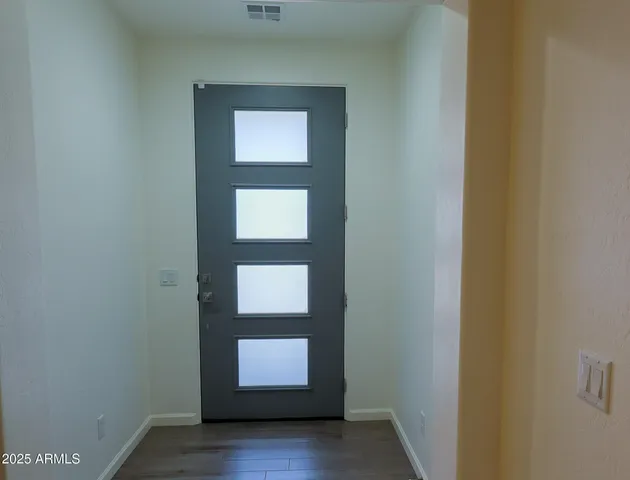 a view of an empty room with wooden floor and mirror