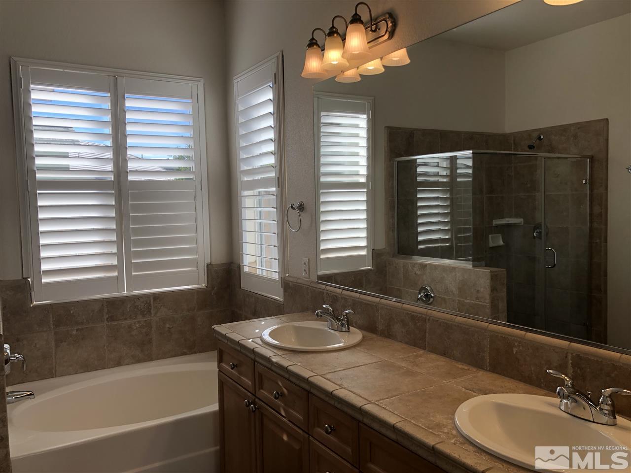 1671 Sewell Drive Reno, NV 89521 - Photo 9 of 16 a bathroom with a granite countertop sink a large mirror and a bathtub
