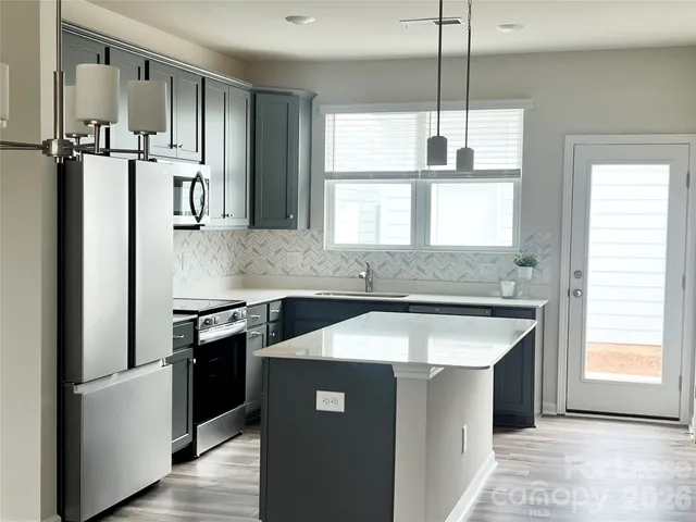 a kitchen with stainless steel appliances granite countertop a sink a stove and a refrigerator