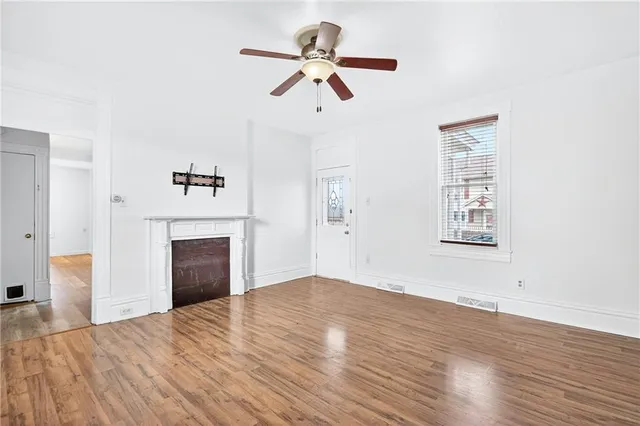 a view of empty room with wooden floor and ceiling fan