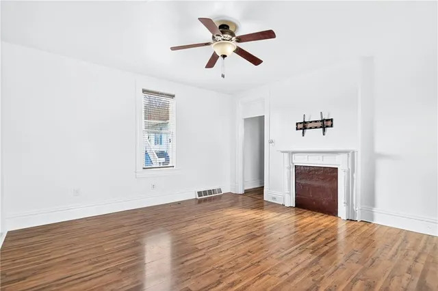 a view of empty room with wooden floor and fireplace