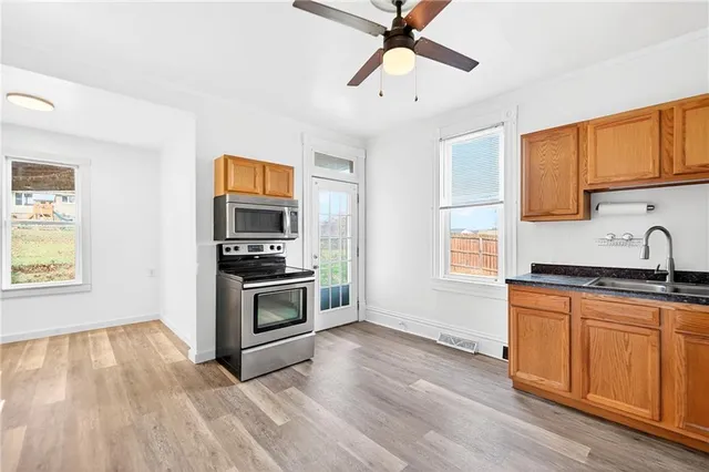 a kitchen with granite countertop a stove top oven a sink and dishwasher with wooden floor