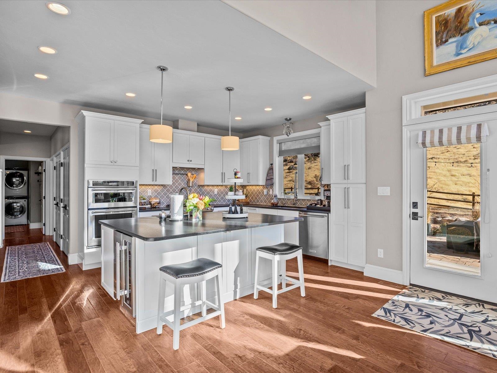 482 Riggs Way Grand Junction, CO 81507 - Photo 7 of 42 a kitchen with stainless steel appliances kitchen island granite countertop a refrigerator oven a sink a dining table and chairs with wooden floor