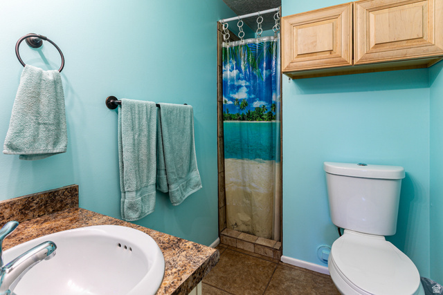 947 Canyon Road, Unit 33 Ogden, UT 84404 - Photo 18 of 19 Bathroom featuring a single vanity with an integrated sink, a tiled shower, and overhead cabinetry