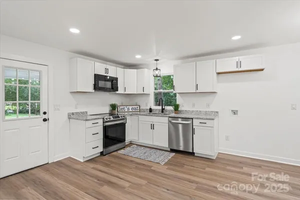 a kitchen with granite countertop a stove top oven sink and cabinets