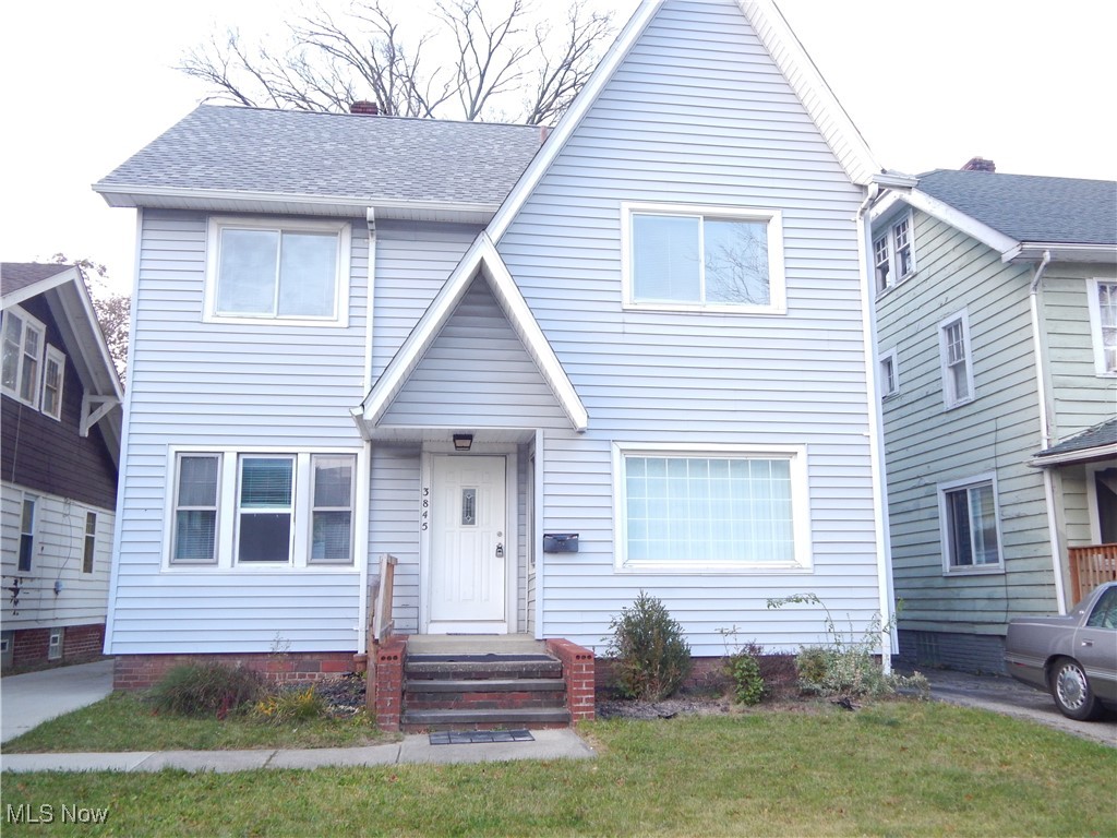 View of front of property featuring a front yard and roof with shingles
