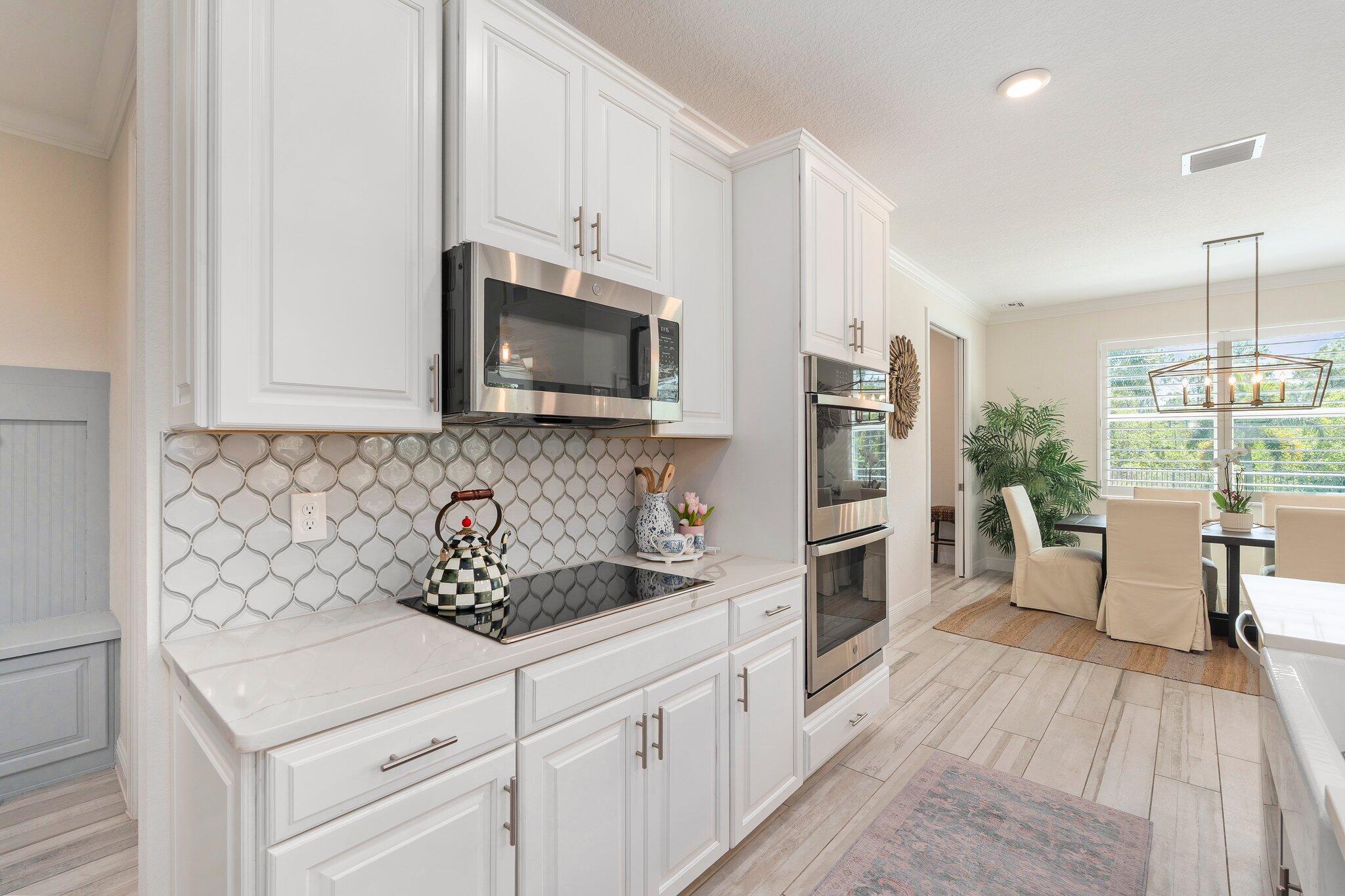 4701 Southwest Ardsley Drive Stuart, FL 34997 - Photo 9 of 83 a kitchen with stainless steel appliances white cabinets a sink a stove a microwave and wooden floors
