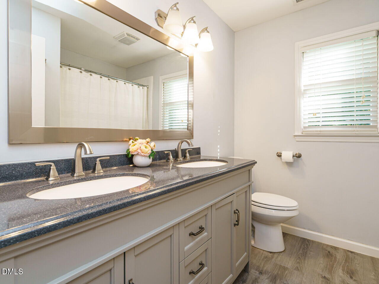 4104 Betterton Drive Raleigh, NC 27613 - Photo 19 of 32 a bathroom with a granite countertop toilet a sink and a mirror
