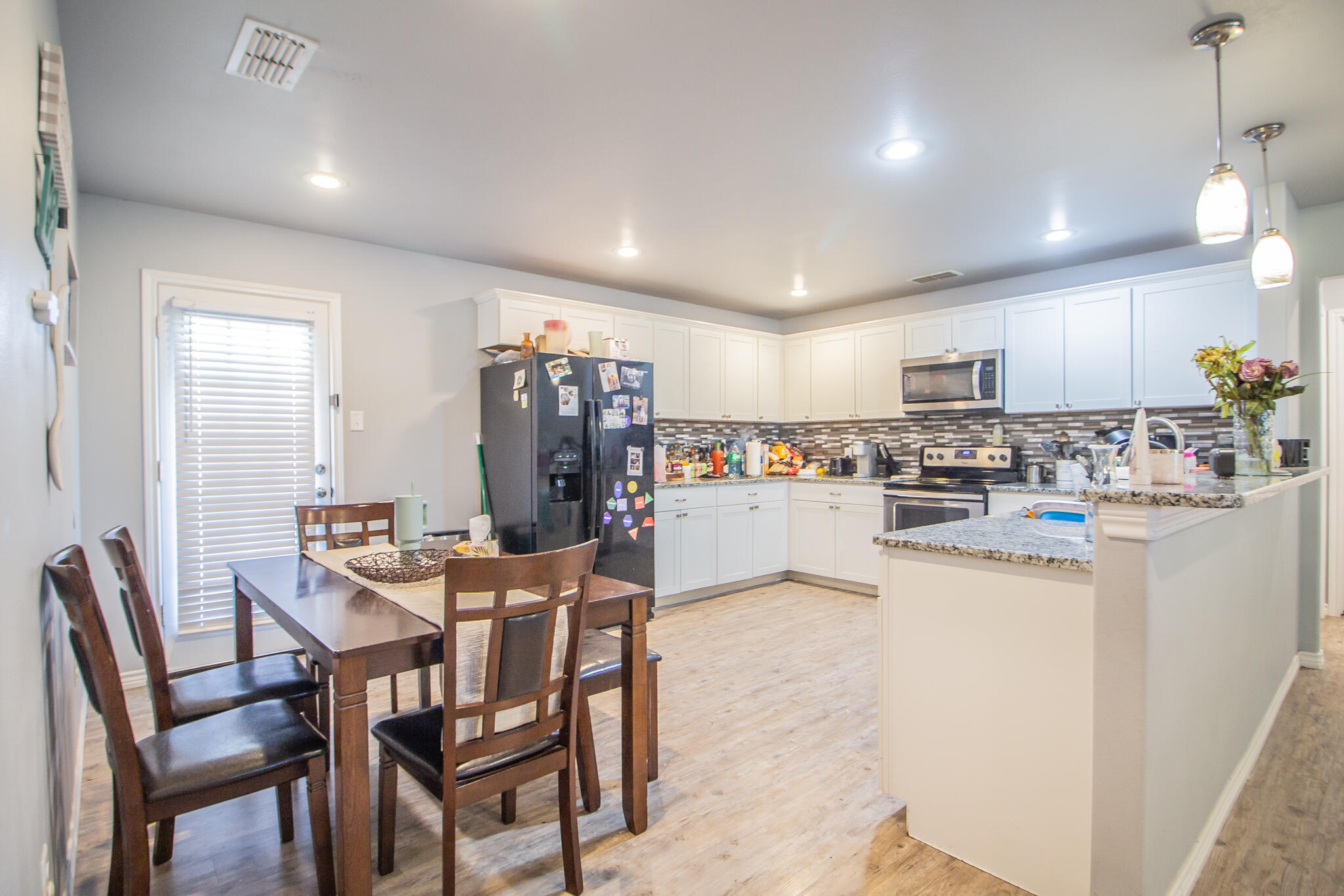 8812 15th Street Lubbock, TX 79416 - Photo 6 of 16 a kitchen with a dining table chairs refrigerator and cabinets