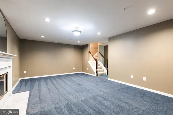 a view of an empty room with wooden floor and a fireplace