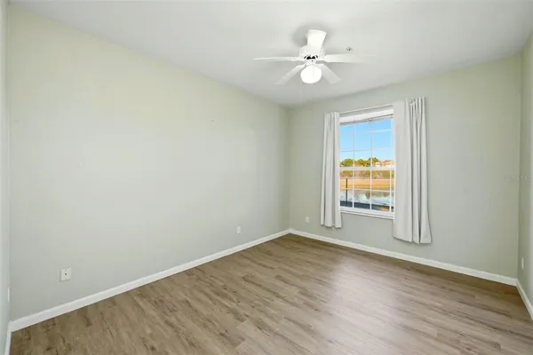 an empty room with wooden floor and fan