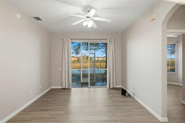 an empty room with wooden floor chandelier fan and windows