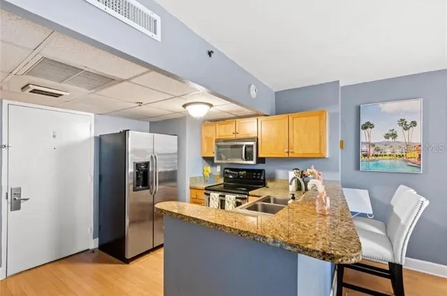 a kitchen with stainless steel appliances granite countertop a sink refrigerator and cabinets