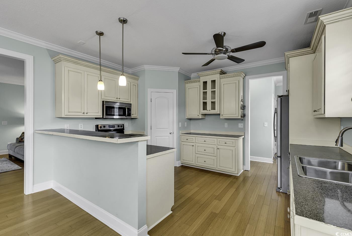 6 Cottage Drive Murrells Inlet, SC 29576 - Photo 10 of 31 Kitchen with ornamental molding, stainless steel appliances, cream cabinets, hanging light fixtures, and dark hardwood / wood-style floors