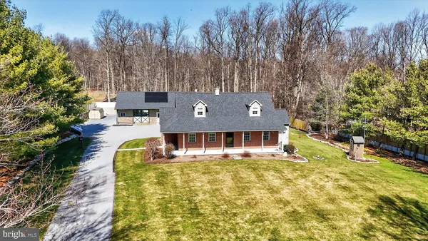 an aerial view of a house with swimming pool and large trees