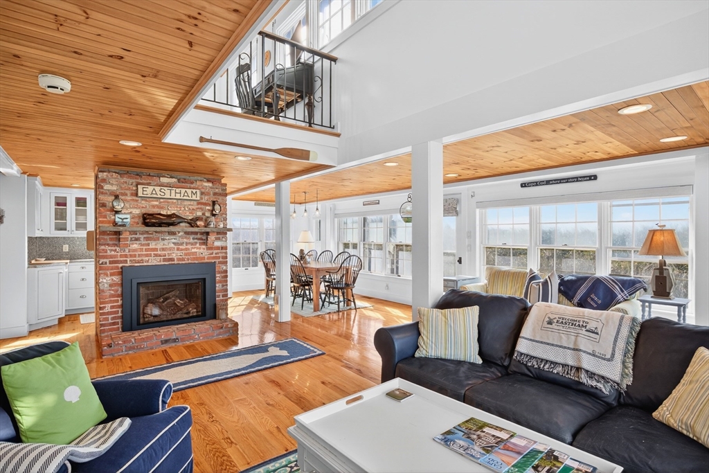 1145 Kingsbury Beach Road Eastham, MA 02642 - Photo 11 of 42 a living room with furniture a fireplace and a table