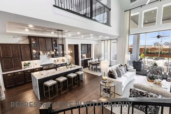 a living room with stainless steel appliances furniture a rug and a kitchen