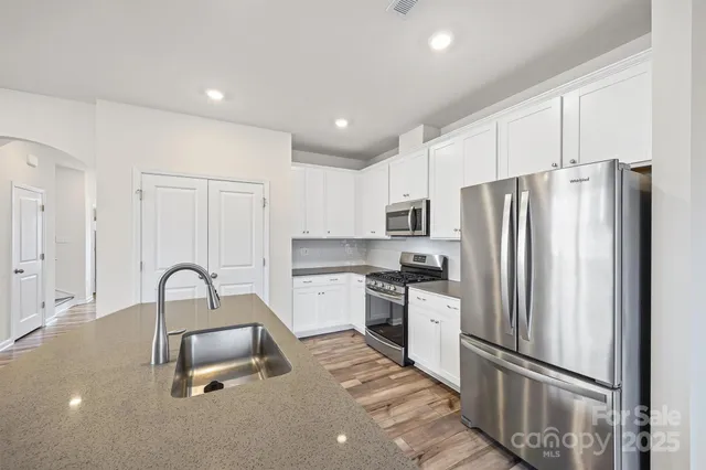 a kitchen with granite countertop a refrigerator and a stove top oven