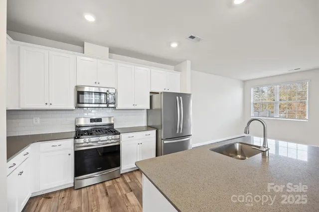 a kitchen with stainless steel appliances granite countertop a sink stove and refrigerator