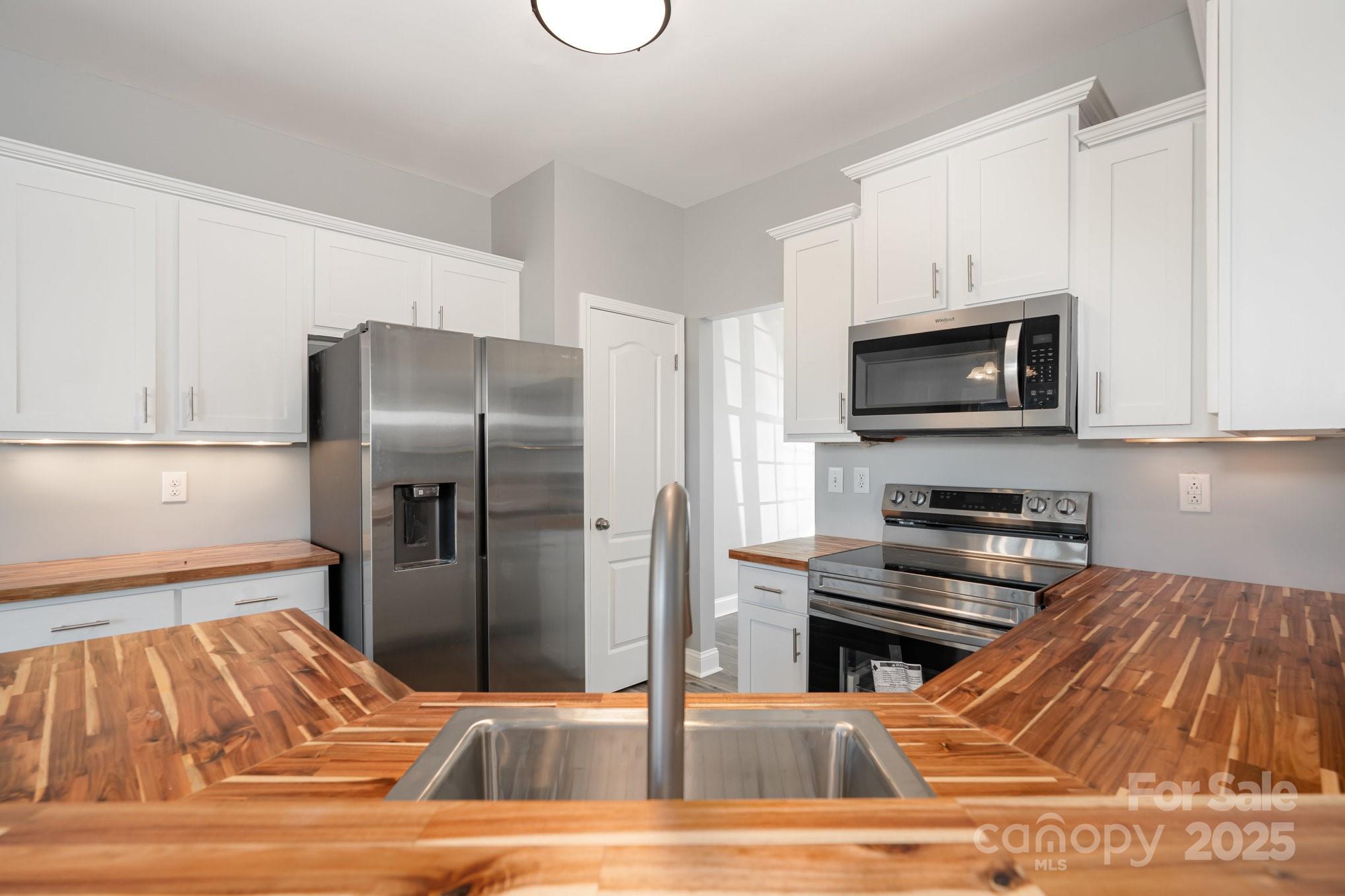 1457 Jc Raulston Court Hickory, NC 28602 - Photo 8 of 39 a kitchen with stainless steel appliances kitchen island granite countertop a refrigerator and a stove top oven