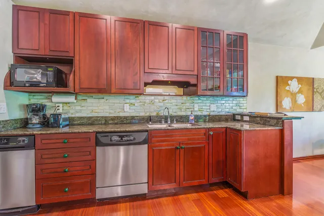 a kitchen with granite countertop wooden cabinets a sink and dishwasher