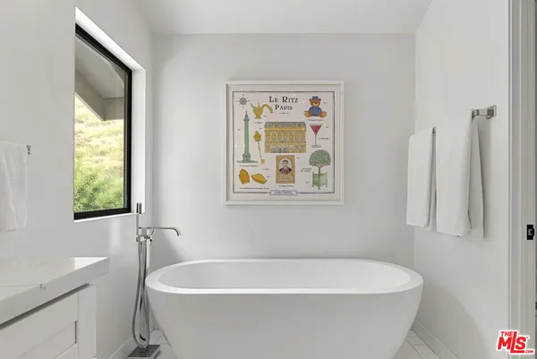 a white bath tub sitting in a bathroom next to a window