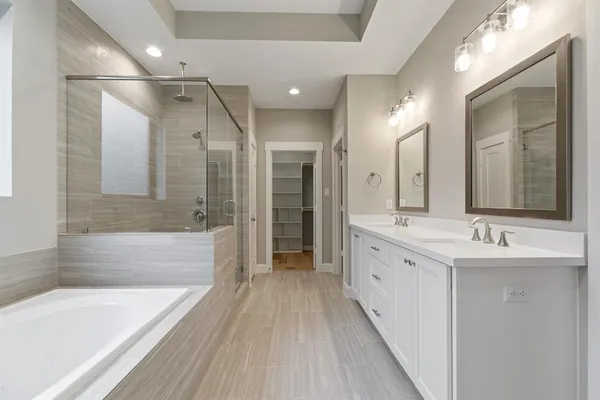 a bathroom with a double vanity sink and mirror with bathtub