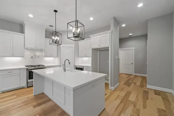 a large kitchen with stainless steel appliances granite countertop a sink a stove and a wooden floors