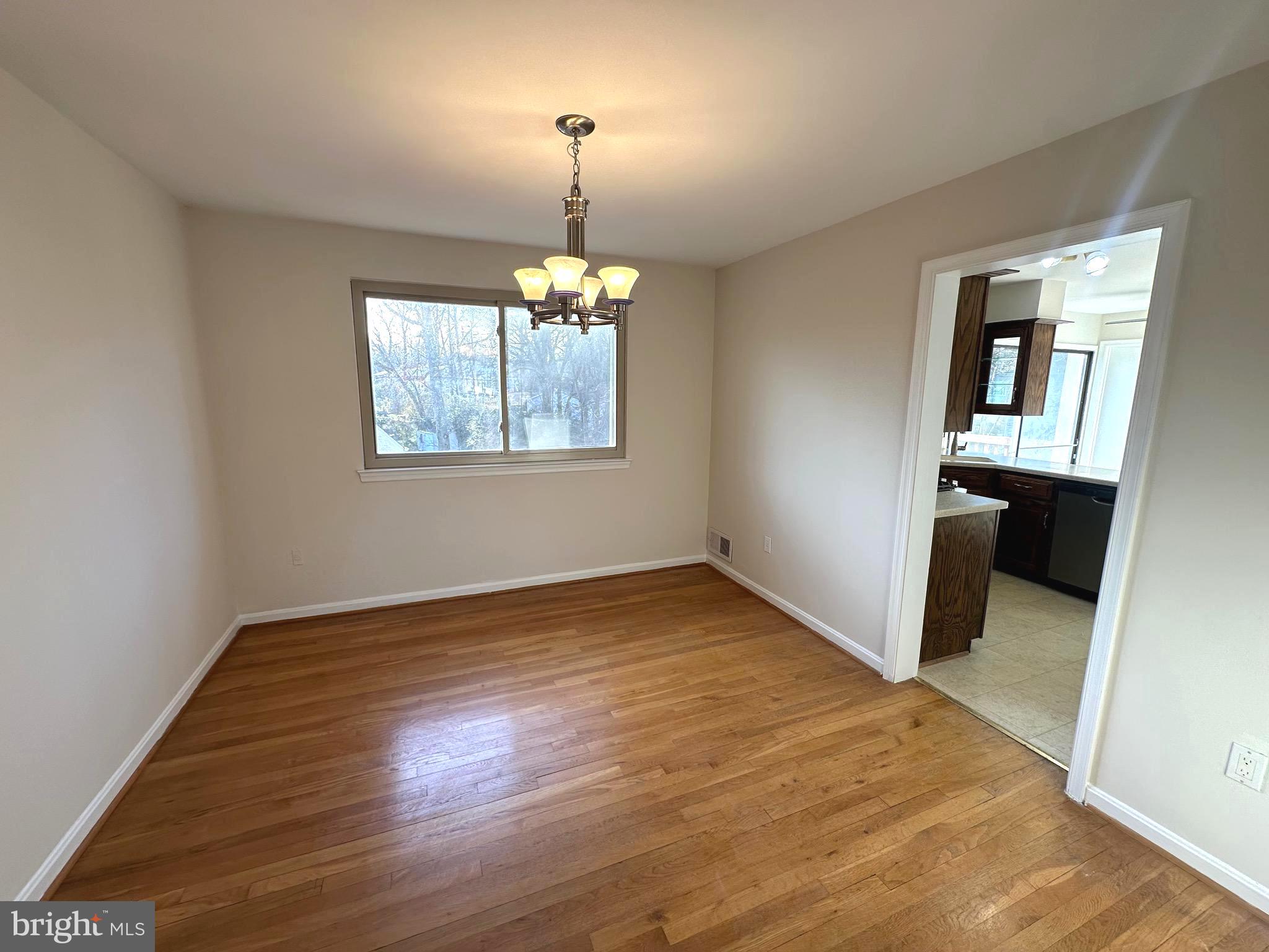 8601 Kenilworth Drive Springfield, VA 22151 - Photo 12 of 47 an empty room with wooden floor chandelier and windows